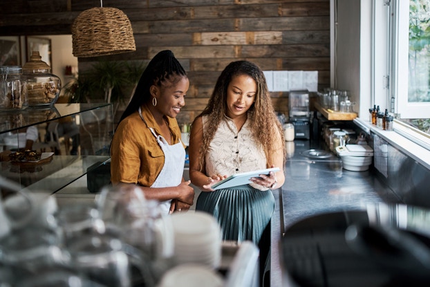  A woman coffee shop worker and owner review the daily lunch menu for the day.