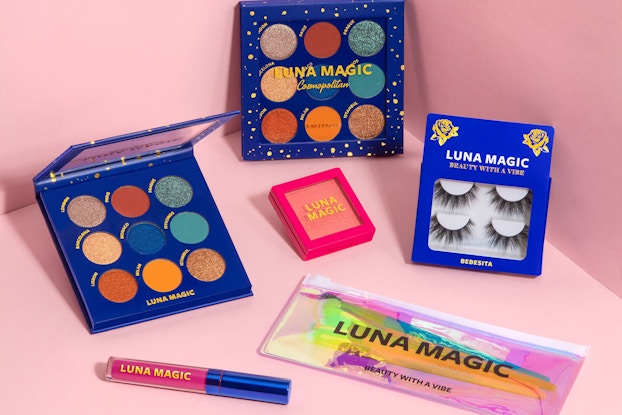 Close-up shot of Luna Magic cosmetics, including an eyeshadow palette, blush, eyelash extensions, and lip gloss.
