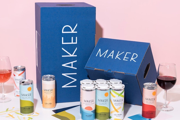 Display of colorful canned wine by Maker Wine in front of a Maker royal blue box with a pink background.