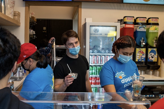 Busy ice cream shop with three employees serving customers