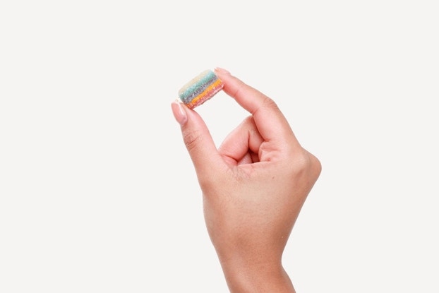 Person's hand holding a gummy from Neutrogena Skinstacks.