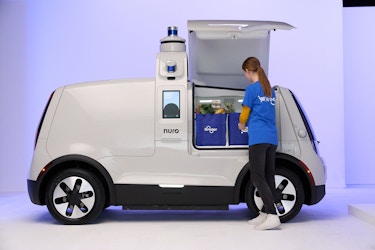  Kroger employee putting grocery bags into a Nuro driverless delivery vehicle. 