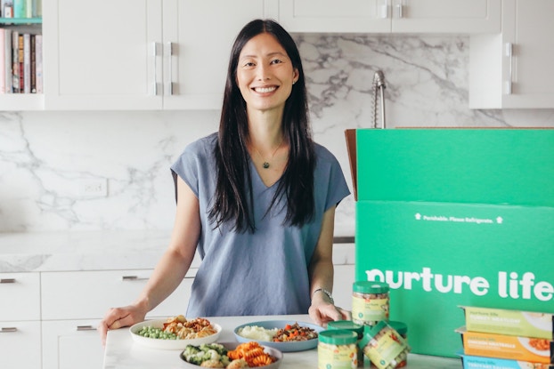 Jennifer Chow, co-founder of Nurture Life, posing in a kitchen with the unboxed meals.