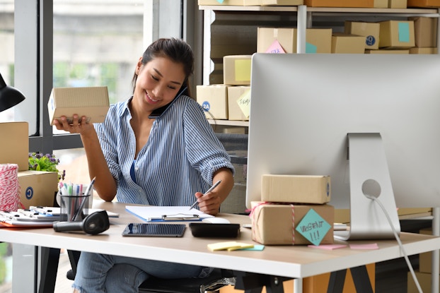 Woman entrepreneur processes online sale with product in hand