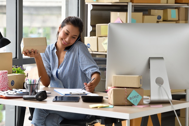  Woman entrepreneur processes online sale with product in hand