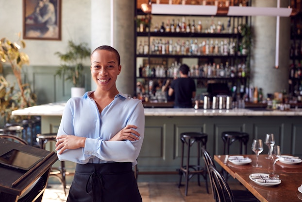  Portrait of confident female owner of restaurant bar standing by hostess stand