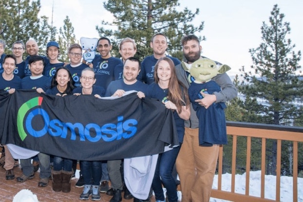 Group of colleagues stand on deck with company banner
