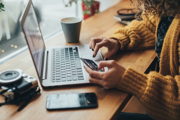 person holding credit card while shopping online via laptop