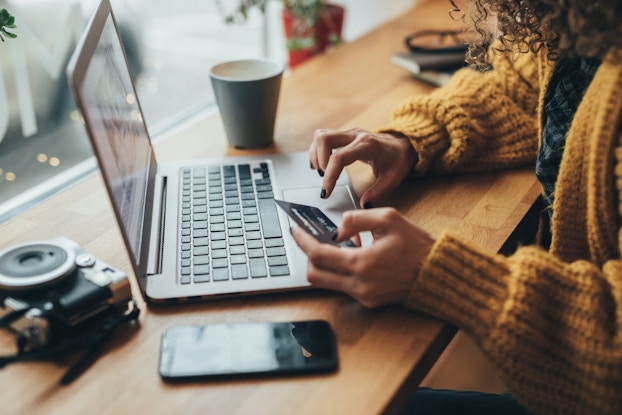  person holding credit card while shopping online via laptop