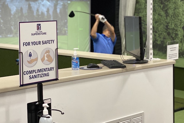  Golf simulator next to complimentary hand sanitizer at a PGA TOUR Superstore location.