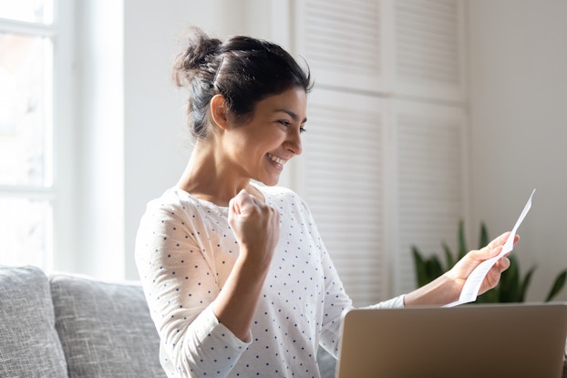 woman smiling reading a letter in living room
