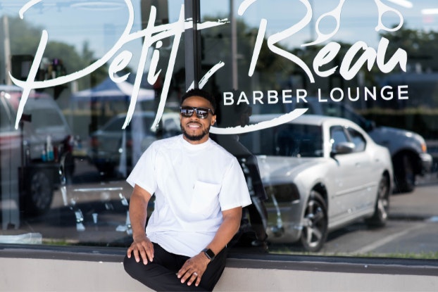  Headshot of Perry Petit Beau, founder of Petit Beau Barber Lounge, standing in front of his storefront.