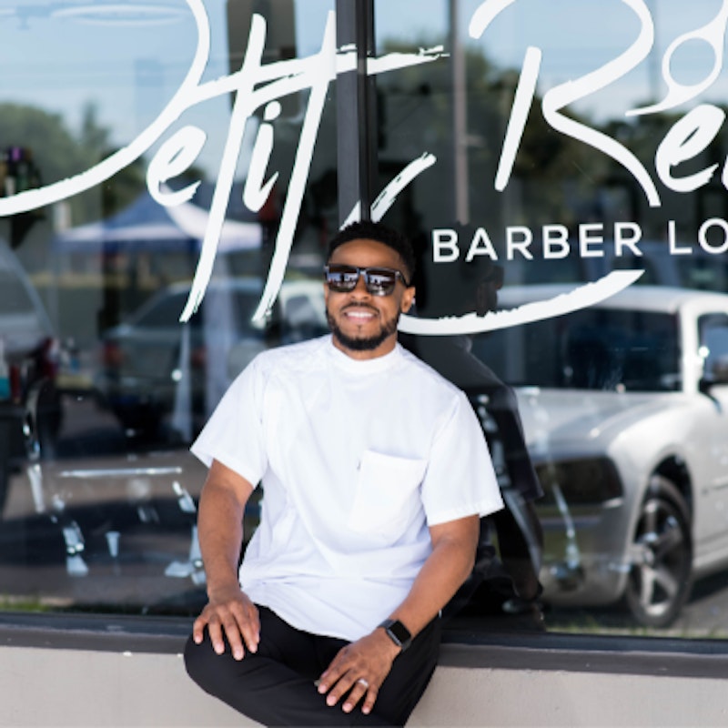 Headshot of Perry Petit Beau, founder of Petit Beau Barber Lounge, standing in front of his storefront.