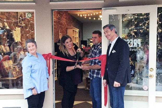 Business owners open their storefront at a ribbon-cutting ceremony