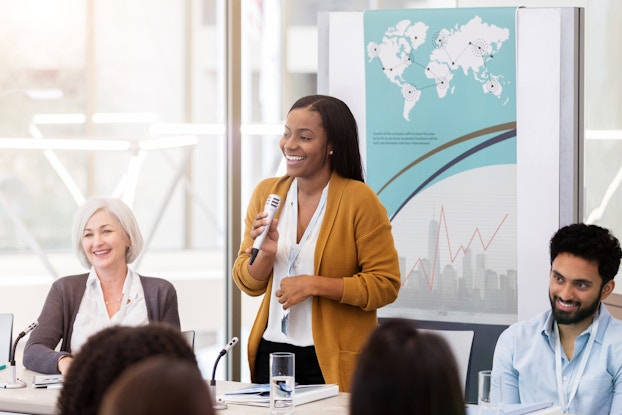  Young business woman moderates a panel discussion at a live event