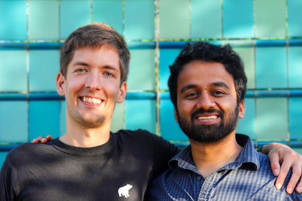 A two-shot of Bjarke Felbo (left) and Sanjay Guruprasad, the Co-founders of indie gaming company Rune, standing and smiling with an arm around the other's shoulder.