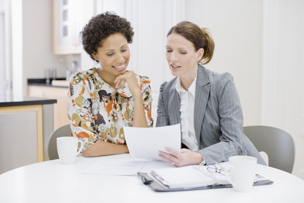 Businesswoman reviews paperwork with woman.