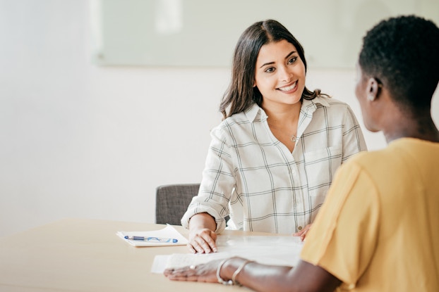  Two women in a meeting sitting at a table.