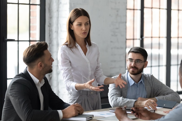  Businesswoman speaks to group in modern conference room