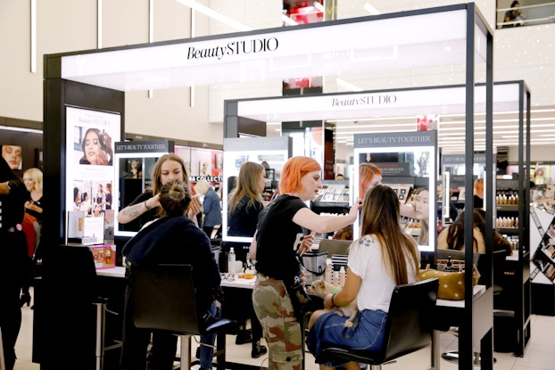 Customers getting makeovers by employees inside a Sephora location.