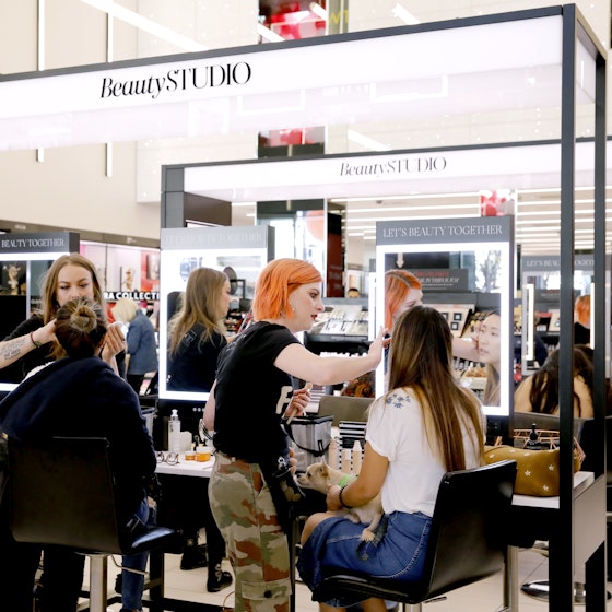Customers getting makeovers by employees inside a Sephora location.