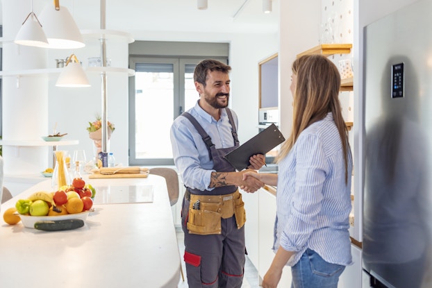 Handyman shakes client's hand after completing a job.