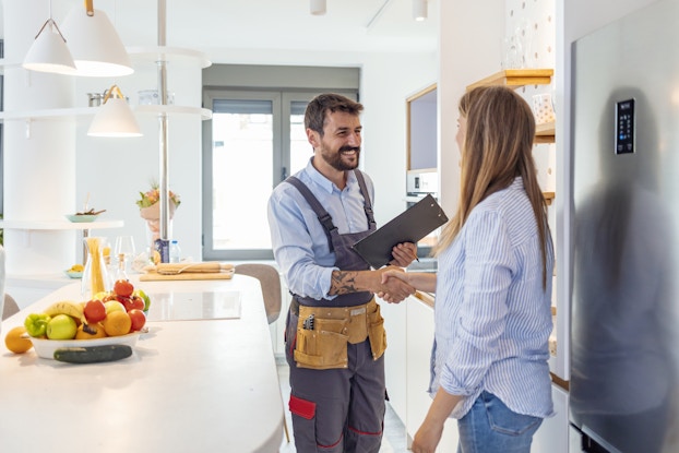  Handyman shakes client's hand after completing a job.