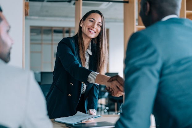  Woman smiles and shakes the hand of a new employee