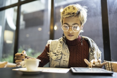  Young businesswoman wearing glasses calculates costs in a cafe. 
