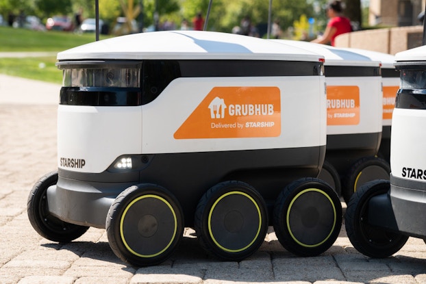 Starship driverless delivery vehicle with Grubhub branding on it.