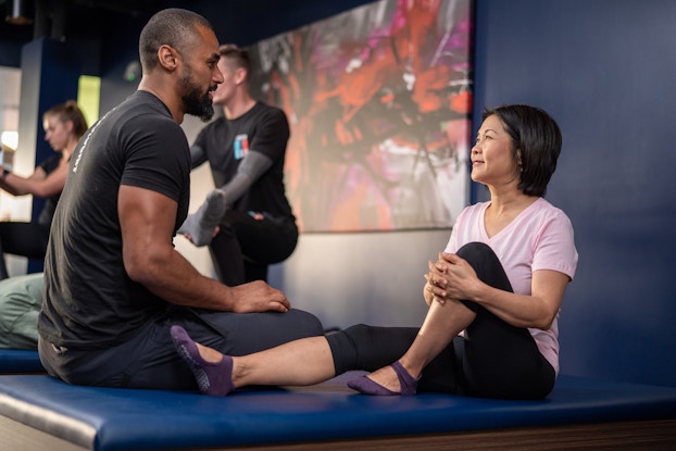  Client on a table working with a professional at a StretchLab location.