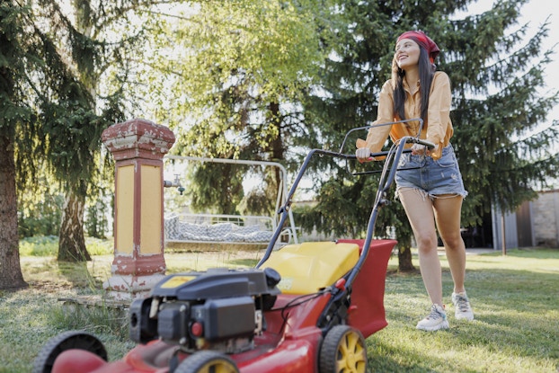  Teenager uses a lawnmower in a backyard.
