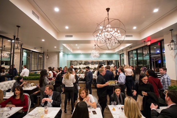  Modern restaurant with high ceilings and a chandelier is bustling with customers