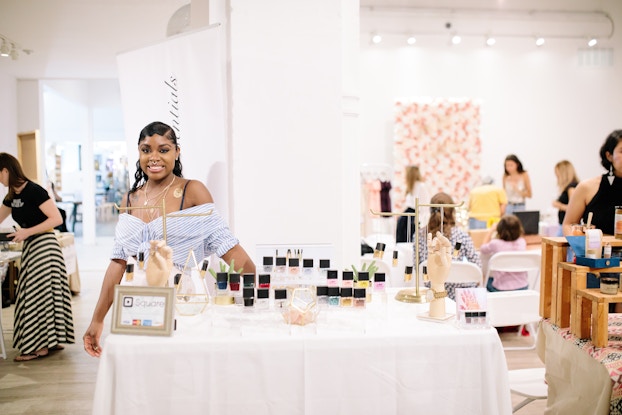  Tanisha Lawrence, founder of Law Beauty Essentials, standing at a product display.