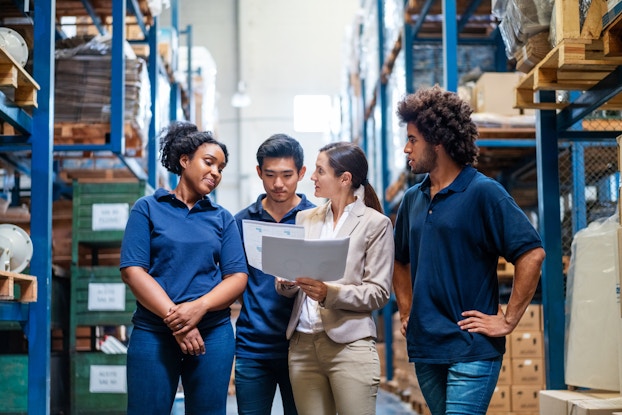  Warehouse manager explains schedule to three employees