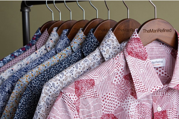  Multi-colored men's dress shirts hang on clothing rack
