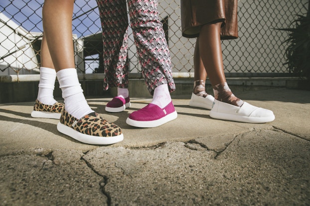  Three models' feet modeling Toms sneakers.