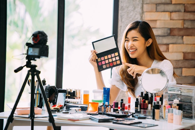  Beauty blogger presenting makeup cosmetics in front of camera