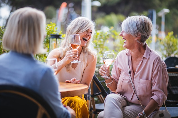  Women laugh over wine at an outdoor restaurant