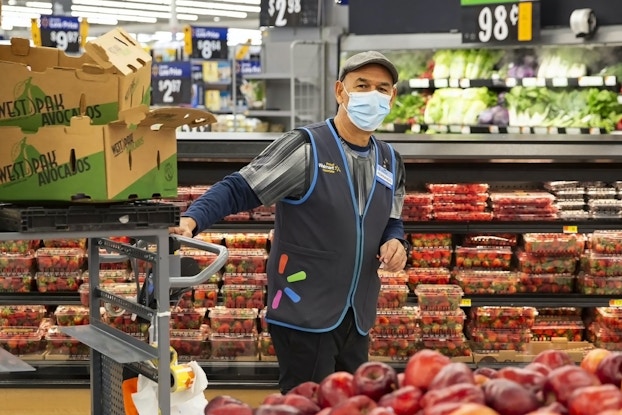 Walmart employee working with mask on in the produce section.
