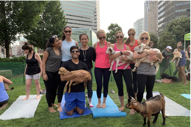Group of people in athletic clothing pose with animals in a park