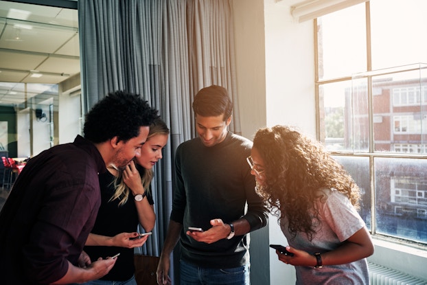  A group of people looking their smartphones in an office