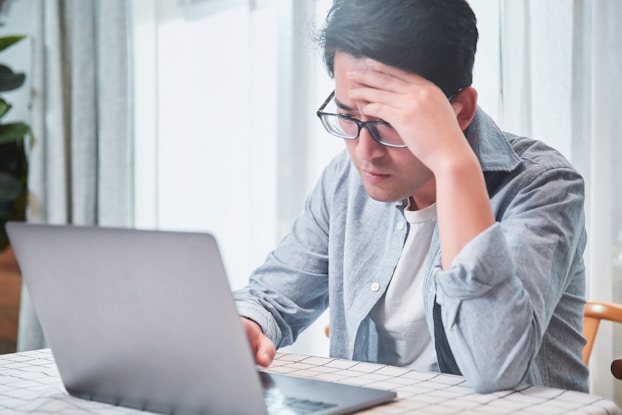 Worried man looks at laptop
