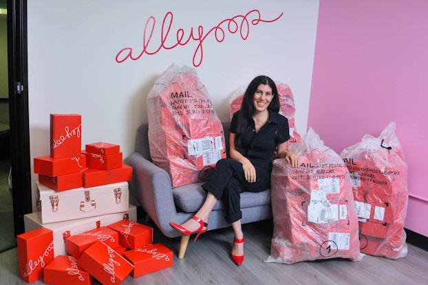 Alleyoop CEO and founder, Leila Keshani, sitting on a couch surrounded by bags of her products.