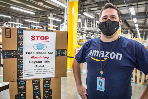 amazon employee wearing mask next to covid-19 safety sign