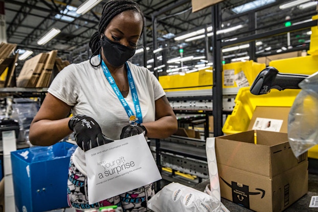  amazon employee in mask and gloves packing items