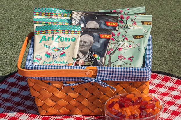  Display of fruit snacks by AriZona Beverage Co. in a basket on top of an outdoor picnic table.