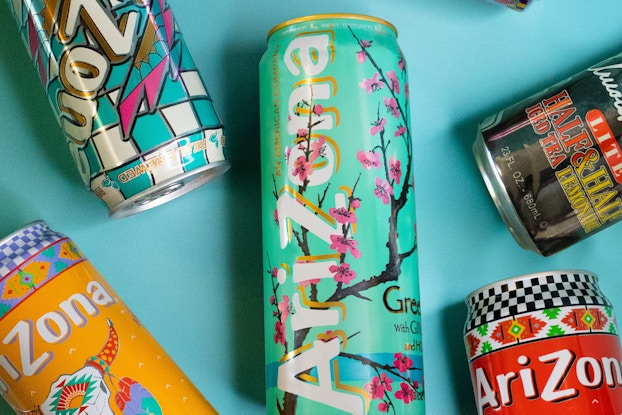  Colorful cans of AriZona Beverage Co.'s iced tea laid on a blue tabletop.