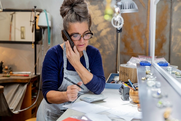 Goldsmith talking on the phone with a customer.