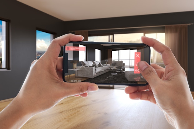 Person using an augmented reality app on their phone to picture furniture in their space before buying.
